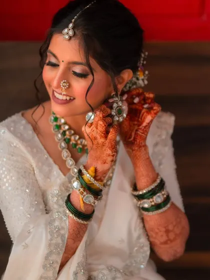A candid moment of the bride getting ready. Her soft glam makeup, with shimmery eyelids and a gentle smile, shows her excitement for the day ahead.