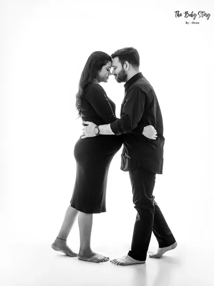 A full-length black and white shot of the couple in a gentle embrace. The high-key white background keeps the image clean and focused on their connection.