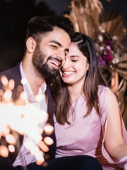 A candid, happy moment between the couple, with the warm light of sparklers adding to the magic of their proposal night.