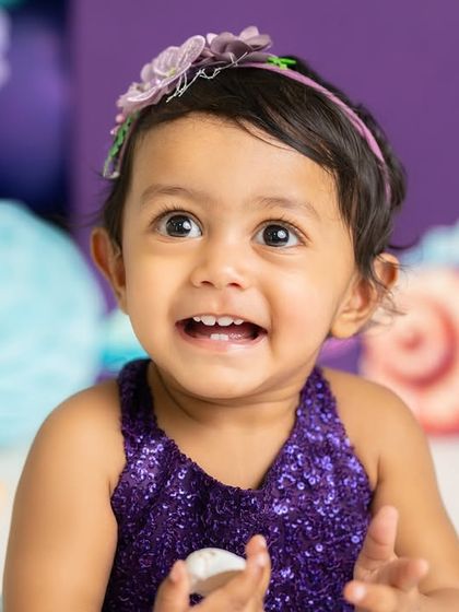 The happiest little mermaid on her first birthday. Her joyful expression is the centerpiece of this vibrant purple and teal under-the-sea themed shoot.
