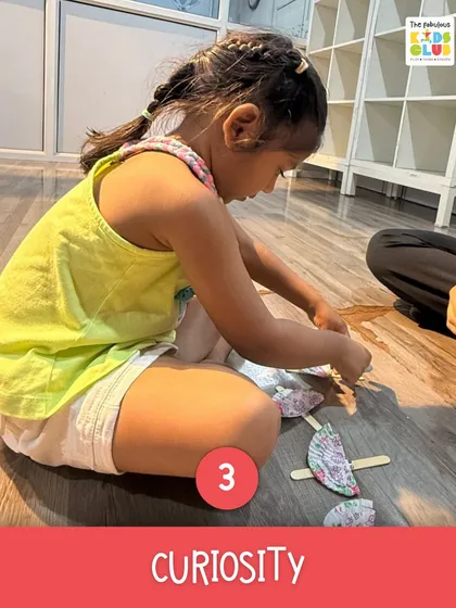 Curiosity is the engine of learning. Here, a child is deeply focused on her craft project, figuring out how different pieces fit together. This is problem-solving in its purest form.