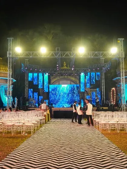 A grand outdoor stage setup for a Sangeet night, complete with a large LED screen backdrop and professional lighting rig. This creates a concert-like feel for the performances.