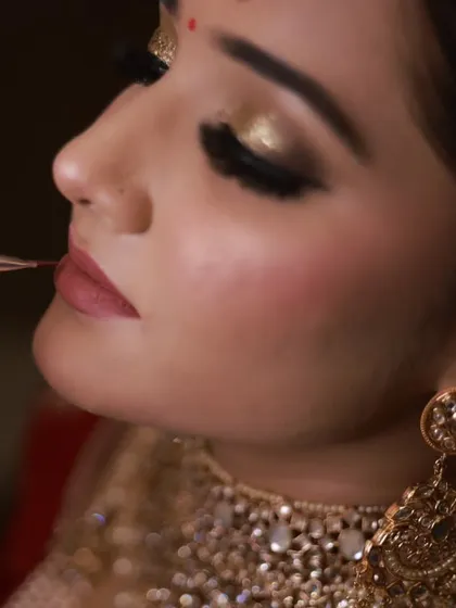 A detailed shot of a makeup artist applying lipstick with a brush. Precision is key in professional makeup application, especially for creating sharp, defined lips that last through the ceremony.