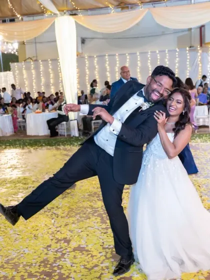 Pure, unadulterated fun on the dance floor. This candid shot captures the groom's playful energy and the couple's laughter, surrounded by a carpet of flower petals.