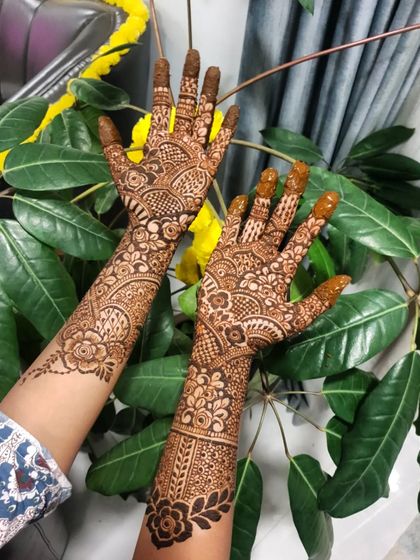 This shot highlights the rich color of the organic henna paste against the lush green background.