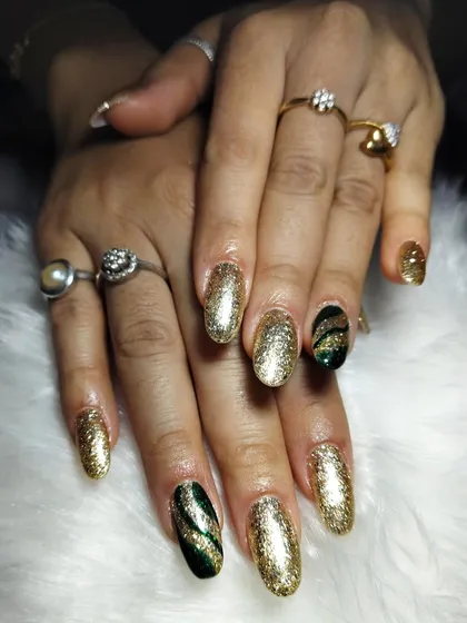 Elegant nail art with a golden glow. This design combines full-coverage gold glitter nails with accent nails featuring a green and gold cat-eye effect.