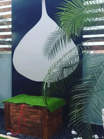 A unique wall art piece with a large, modern graphic, set behind lush palm plants.