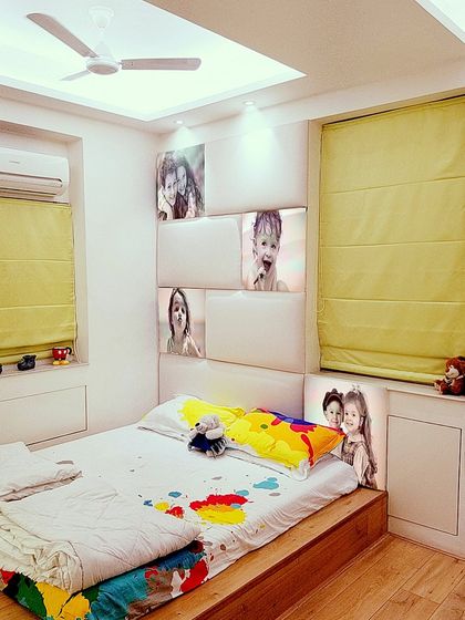 We designed this kid's room with a custom headboard featuring built-in light panels with family photos. The colorful bedding and playful details make it a fun and personal space for a child.