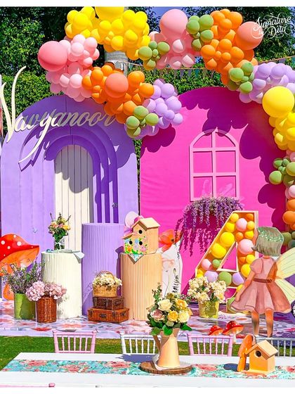A close-up of the main Fairyland backdrop, featuring the birthday girl's initial 'N' and a small fairy cutout. The mix of balloons, florals, and custom props creates a rich, textured look.