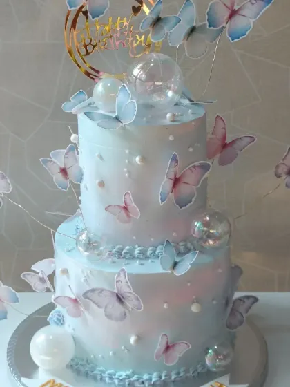 A dreamy two-tiered cake adorned with a flight of delicate wafer paper butterflies. The pearlescent finish gives it a magical shimmer.