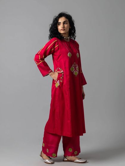 A side view of the red kurta set, showing the placement of the unique embroidered motifs and the comfortable, straight-fit pants.