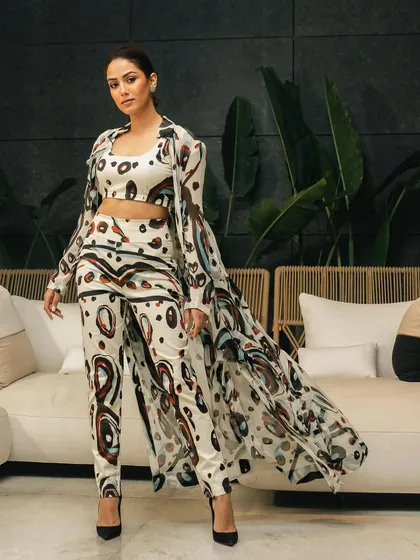 A full-length fashion portrait of Mira Kapoor. The clean interior setting and soft lighting create an elegant and sophisticated look.