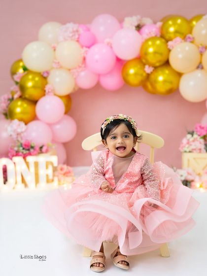 A classic and beautiful first birthday portrait. Dressed in a stunning pink gown, she looks like a true princess celebrating her special day.