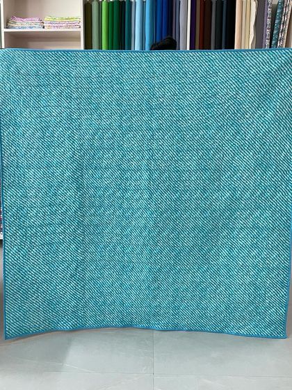 The back of the quilt, showing a simple teal fabric.