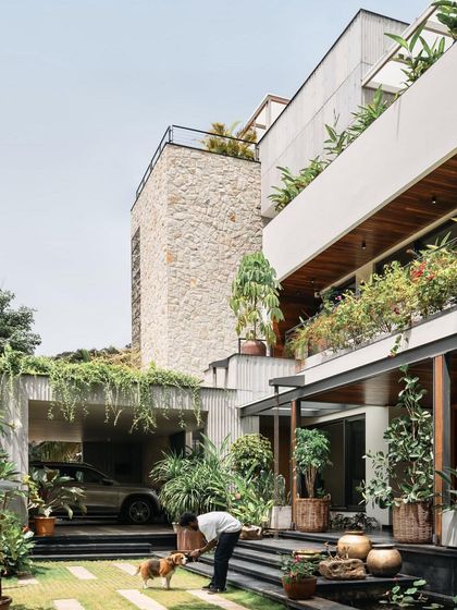 The home is designed to embrace its lush, green surroundings, with cascading plants on multiple levels and a seamless flow between the house and garden.