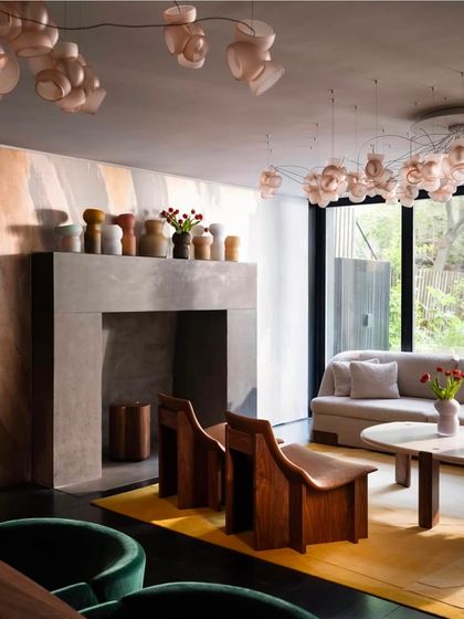 A living room featuring two different installations of the Bocci 100 series, one as a ceiling fixture and another as a sprawling canopy, demonstrating the system's versatility.