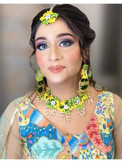 A close-up of a Mehendi makeup look. We used a colorful palette to match her floral jewelry and outfit, with bold blue and green eyeshadow for a playful and festive style.