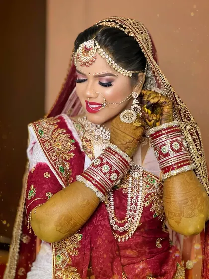 A close-up shot capturing the details of the hathphool, bangles, and the intricate work on her traditional Gujarati bridal attire.