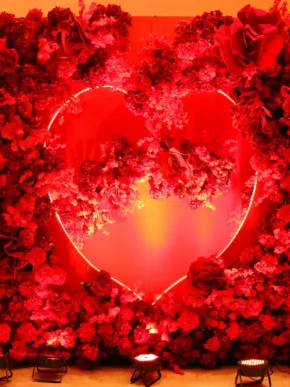 A photo booth that’s all about love. This heart-shaped neon light set within a wall of red roses was a popular spot for guests to capture memories at this passionate, red-themed celebration.