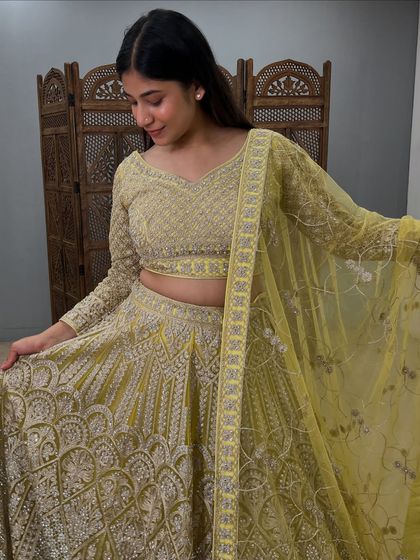 A closer look at the lime green lehenga, showing the intricate embroidery on the skirt and the delicate net dupatta.