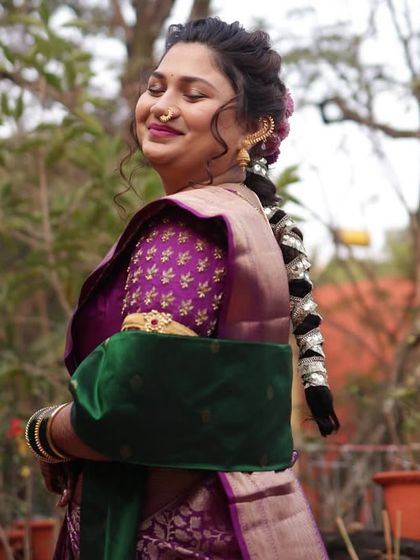 This side profile highlights the traditional Maharashtrian bridal hairstyle, adorned with intricate hair accessories, and the elegant drape of her saree and shawl.