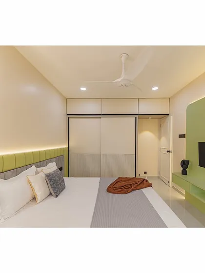A look at the minimalist design of the TV unit and sliding wardrobes. The clean lines and handle-less design contribute to the room's serene and uncluttered aesthetic.