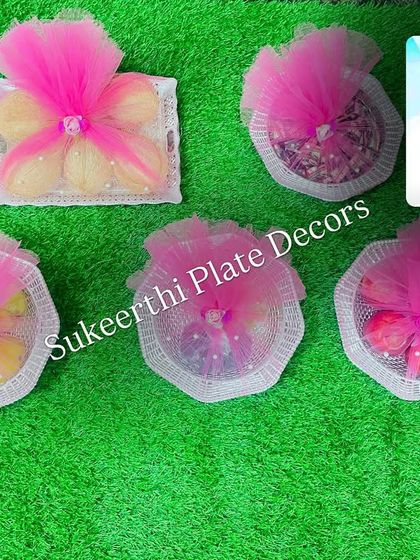 These are simple yet elegant platters I designed for a baby shower in Palladam. Each plate contains different items like sweets and dry fruits, wrapped in pink and white netting to match the celebration's theme.