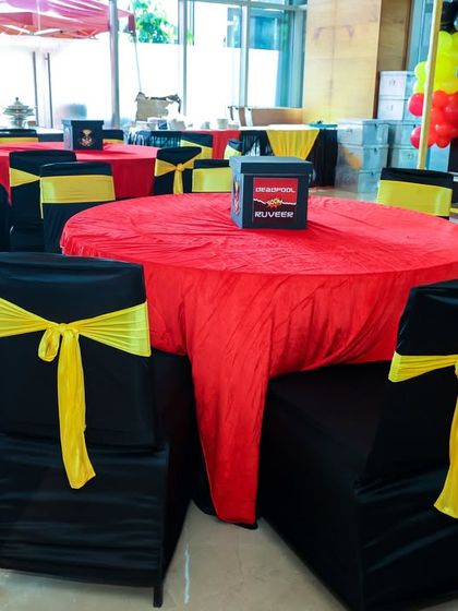 Themed seating arrangement with black and yellow chair covers and red tablecloths to match the Deadpool and Wolverine color scheme.
