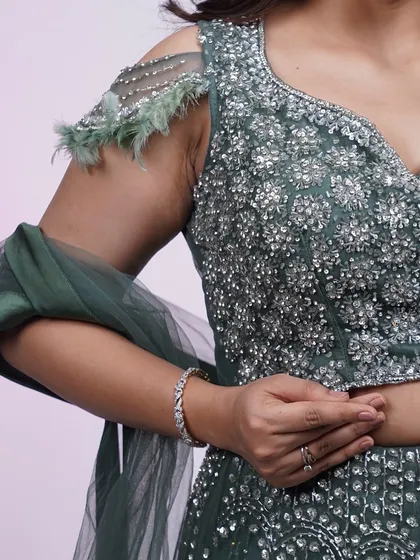 A close-up of the stunning crystal and feather details on the shoulder of our dark green lehenga.