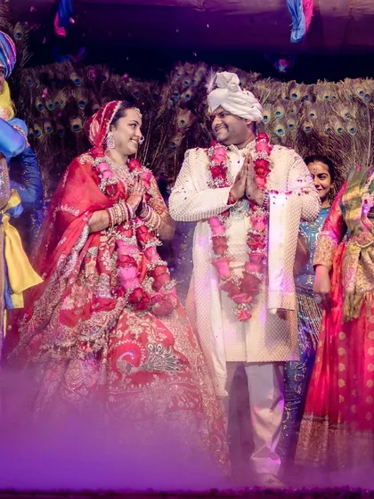 The couple shares a moment of respect and joy, surrounded by performers dressed as Radha and Krishna, fully immersing everyone in the chosen theme.