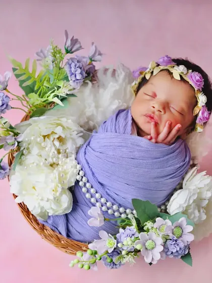 A full view of the lavender floral basket setup, showing the baby nestled among white and purple peonies. This arrangement creates a lush, garden-like feel.