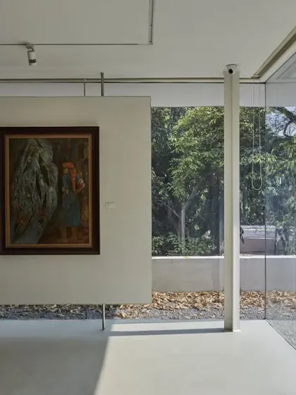 A view from the Batley Gallery at the Kasturbhai Lalbhai Museum. A full-height glass wall provides a clear view of the historic main house, creating a visual connection between the adapted gallery space and the original heritage structure.