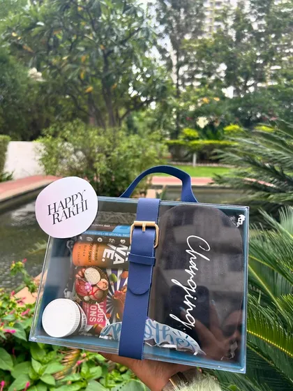 A modern Rakhi hamper for a brother in a clear acrylic box with a blue leatherette strap. These are very popular and easy to customize.