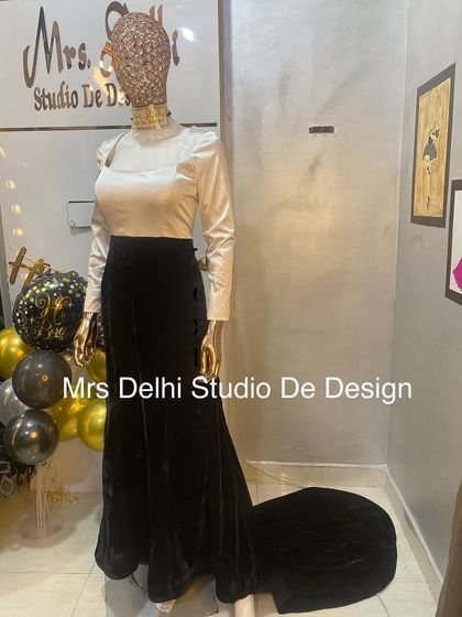 A timeless black and white gown inspired by classic Bollywood style. This piece features a sleek white satin top and a flowing black velvet skirt with a subtle trail, perfect for any formal event.
