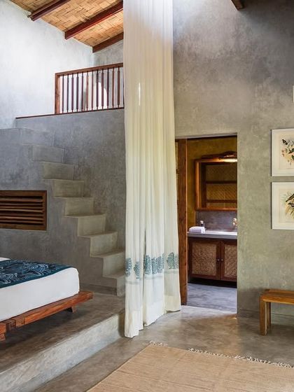 The bedroom of the Garden Suite's blue room, a double-height space with a staircase leading to the mezzanine level. The design uses the building's volume to create a sense of spaciousness.