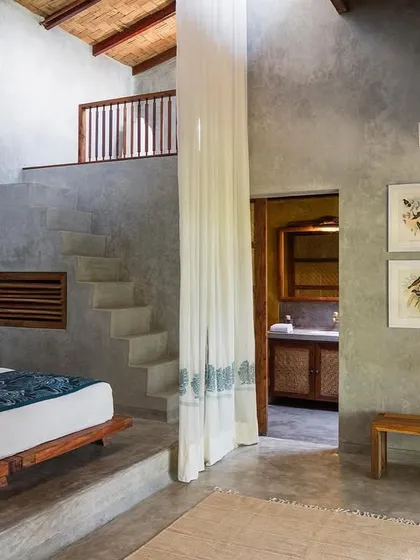 The bedroom of the Garden Suite's blue room, a double-height space with a staircase leading to the mezzanine level. The design uses the building's volume to create a sense of spaciousness.