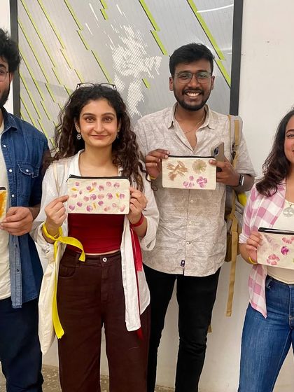 A group of friends proudly displaying the canvas pouches they designed in a flower pounding session. This workshop is a great activity for friends looking for a unique and creative way to spend time together.