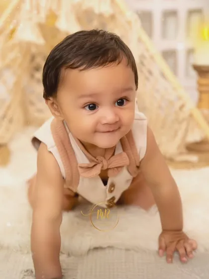 A sweet baby boy crawling on a white fur rug in front of a boho teepee prop.