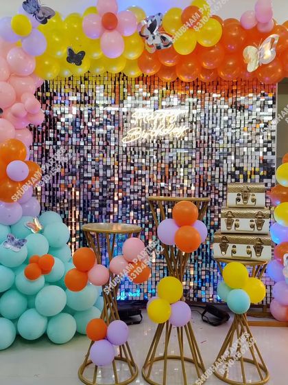 A vibrant and colorful butterfly-themed decoration set against a shimmering silver sequin wall.