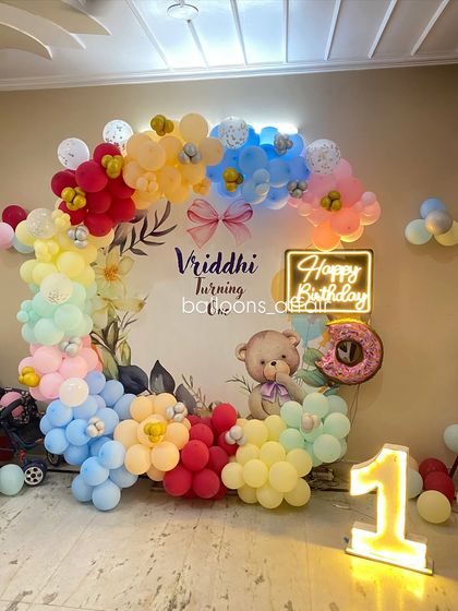 A close-up of the teddy bear and donut foil balloon against the custom floral backdrop.