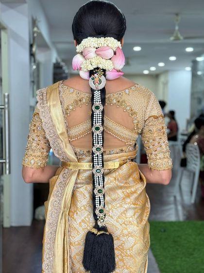 An elaborate bridal braid featuring a pearl and emerald jada, with lotus petal flowers at the base for a unique touch.