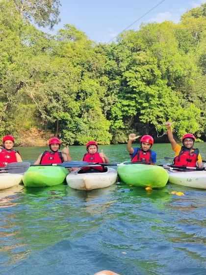 A group of young girls lines up their kayaks and waves, showing the camaraderie built at our camps.
