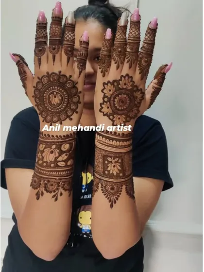 This happy client is showing her matching mehandi designs. The pattern includes a central mandala on the palm with complementary bands on the arms.