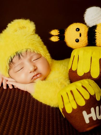 This little one, dressed as a baby bear, sleeps peacefully next to adorable "hunny" pots, bringing a touch of storybook magic to the newborn session.