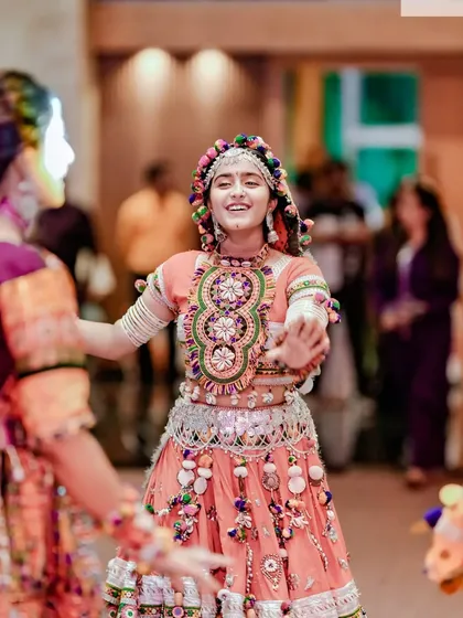 A candid shot of a young woman smiling as she dances Garba, her colorful outfit a blur of motion and joy.