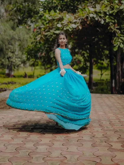 A dynamic shot capturing the joyful twirl of a flowing blue lehenga, embodying the spirit of Radha in a garden setting.