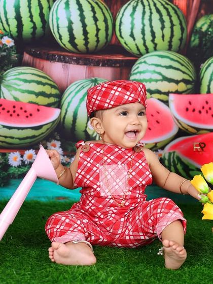 A happy baby girl enjoys the watermelon farm theme, surrounded by fresh melons and garden props. Her joyful expression makes this a truly sweet photo.