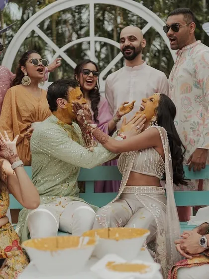 Friends and family playfully applying haldi to the couple. These moments of shared joy and laughter are the essence of the ceremony.