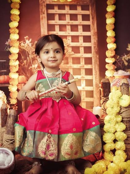 Another lovely shot of our little Radha, surrounded by traditional decorations. We ensure every detail contributes to the festive and spiritual feel of the photoshoot.