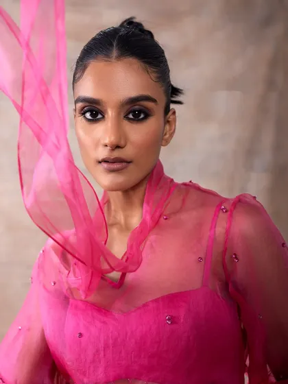 A vibrant pink ensemble from the Akashi campaign. The makeup look, with its defined dark eyes, provides a beautiful contrast to the bright color of the outfit.